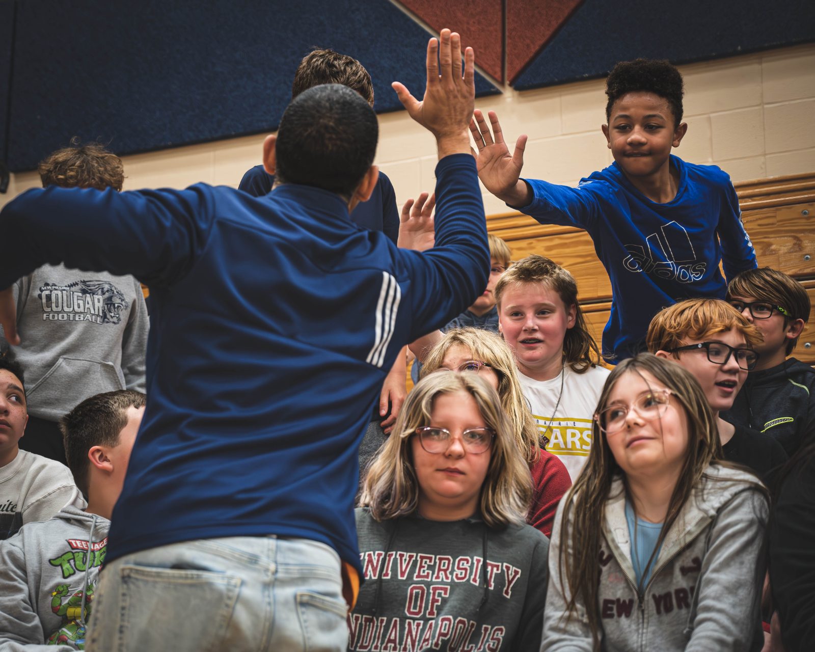 A Five Star Life mentor high-fiving students in a school gym